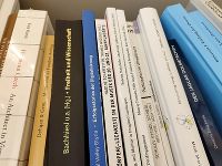 Dargestellt wird ein mit Büchern bestücktes Regalfach